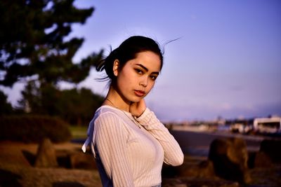Portrait of beautiful woman standing against sky