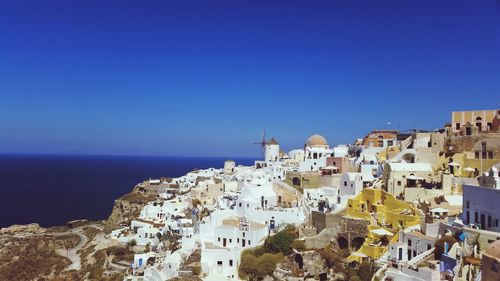 Aerial view of townscape by sea against clear blue sky