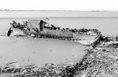 Damaged boat on beach against clear sky