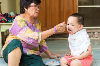 Grandmother feeding cute boy at home