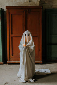 Little ghost sitting in the abandoned house. autumn halloween