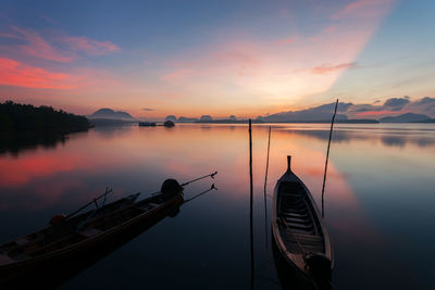 Silhouette boat sailing in lake against sky during sunset