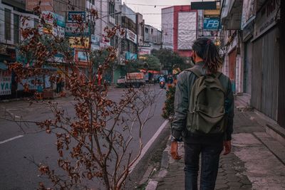 Rear view of man standing on footpath by street in city