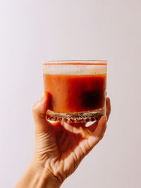 Cropped hand holding drink against white background