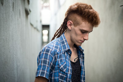 Portrait of young man looking away against wall