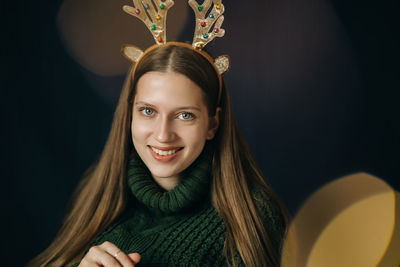 Teenager girl with christmas deer horns in green sweater, rejoices
