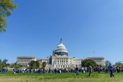 Tourists in front of capitol hill against clear sky