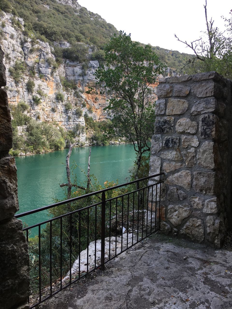 railing, tree, water, mountain, scenics, tranquil scene, tranquility, steps, nature, footpath, non-urban scene, beauty in nature, outdoors, valley, town, remote, day, no people, stone material, cliff