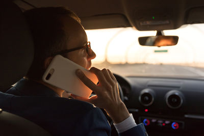 Businessman talking on smart phone while driving car
