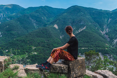 Man sitting on rock looking at mountains