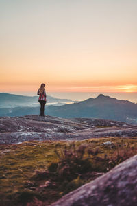 Woman standing on cliff during sunset