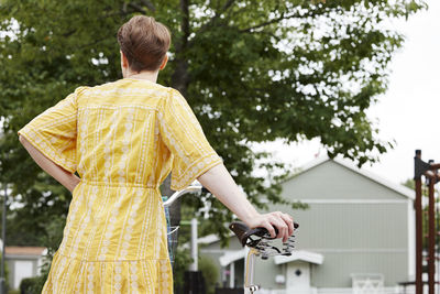 Rear view of woman standing near bicycle