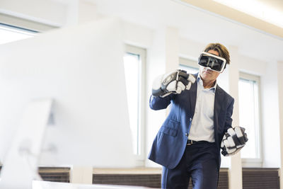 Businessman wearing vr glasses and ice hockey gloves in office