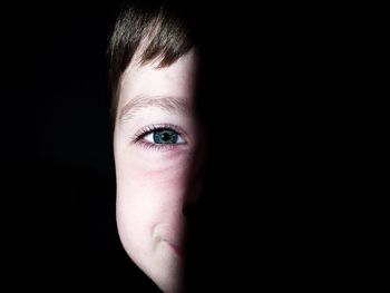 Close-up portrait of boy against black background