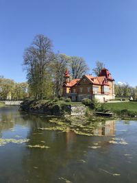 Houses by lake and buildings against clear blue sky