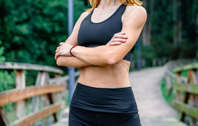 Midsection of young woman standing against blurred background