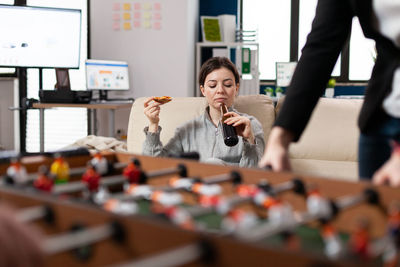 Man playing foosball while woman drinking beer in background