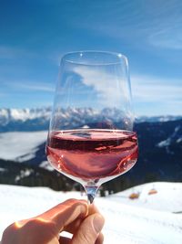 Midsection of person holding beer glass against sky