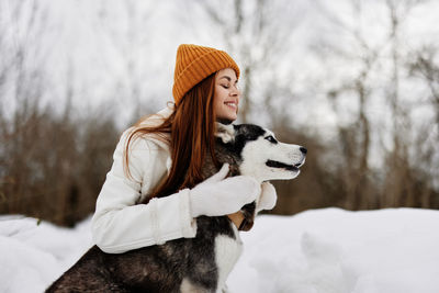 Portrait of young woman with dogs on snow covered field