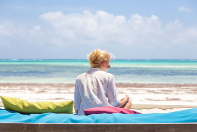 Rear view of man sitting on beach