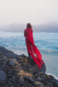 Woman wrapped with red fabric on cliff scenic photography