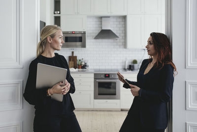 Female colleagues discussing at doorway in home office