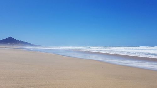 Scenic view of beach against clear blue sky