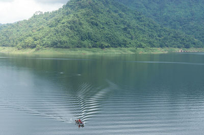 High angle view of people riding boat on lake against mountain