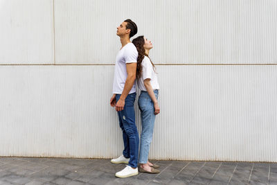 Young couple standing against wall