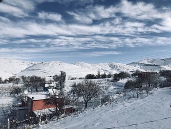 Snow covered houses by buildings against sky