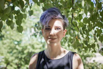 Portrait of smiling teenager girl against tree