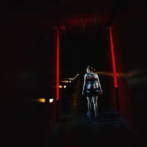 Rear view of woman standing on illuminated walkway
