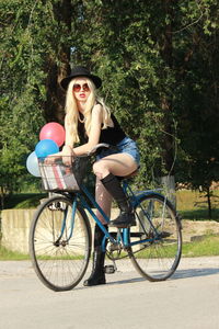 Portrait of smiling woman with bicycle against trees