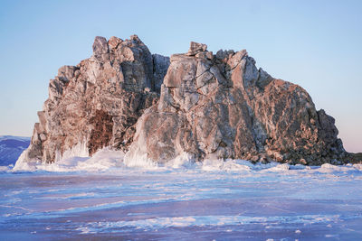 Rock formations in sea against clear blue sky