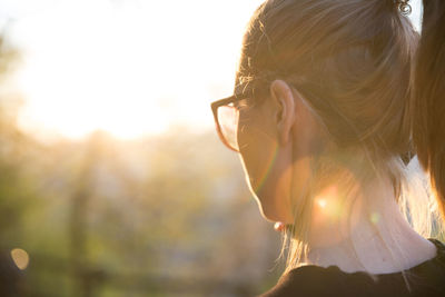 Close-up of woman looking away against sky during sunset