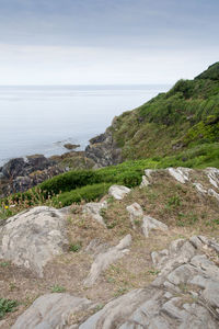 Scenic view of cliff by sea against sky