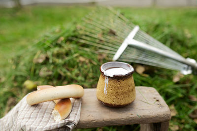 Ceramic cup milk drink draining over the edge on old stool and baking, green collected grass forces