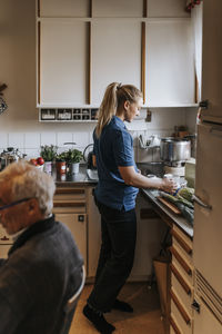 Side view of female healthcare worker preparing coffee while standing in kitchen at home