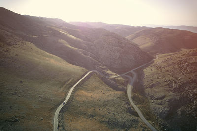 Car is driving along a winding mountain road in early morning. aerial panoramic view of mountains