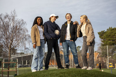 Portrait of teenage friends standing on grass