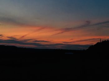 Silhouette landscape against dramatic sky during sunset