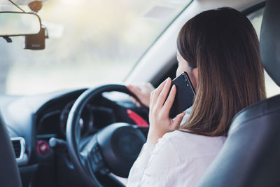 Woman answering smart phone while driving car