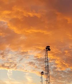 Low angle view of silhouette tower against orange sky