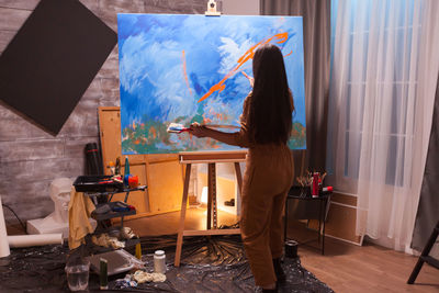 Rear view of woman standing on table at home