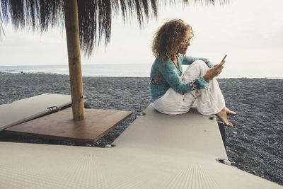 Full length of woman using mobile phone at beach