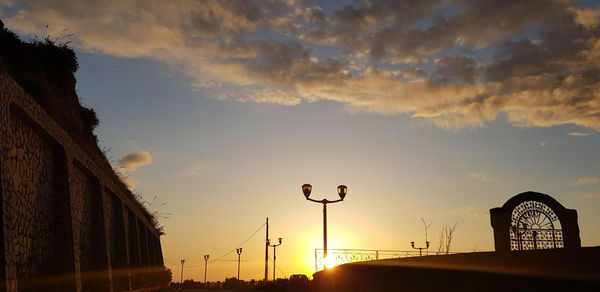 Low angle view of street lights against sky during sunset