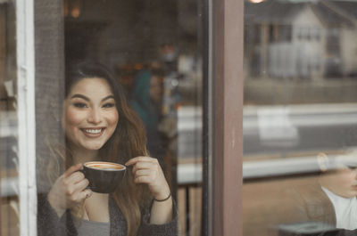 Portrait of young woman holding coffee in cafe