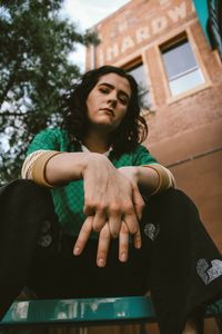 Low angle portrait of young woman standing against built structure