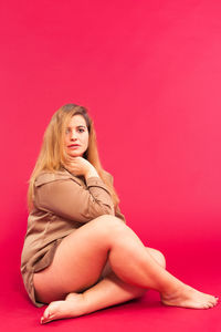 Portrait of seductive woman sitting against maroon background