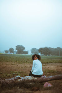 Full length of woman sitting on field against clear sky